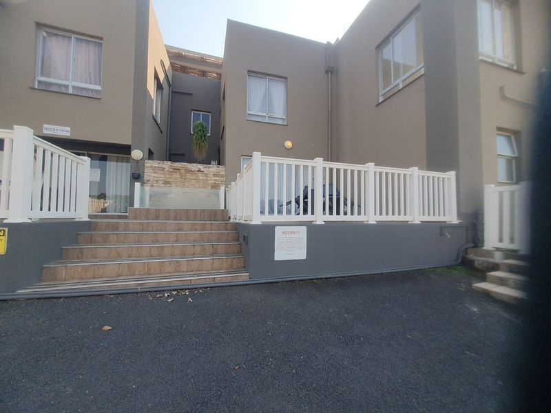 Front exterior view of the property featuring a tiled staircase, white balustrades, and a stone-clad feature wall leading to the entrance.