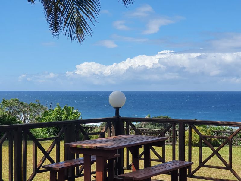 An elevated outdoor patio area featuring a timber balustrade and expansive, unobstructed ocean views.