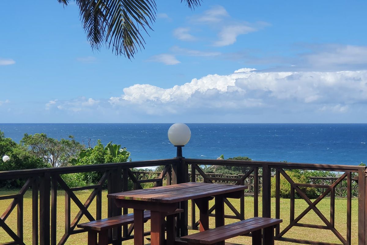 An elevated outdoor patio area featuring a timber balustrade and expansive, unobstructed ocean views.