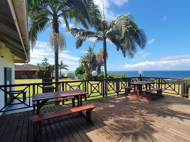 Spacious timber deck featuring a built-in braai, timber balustrades, and expansive ocean views, perfect for outdoor entertaining.