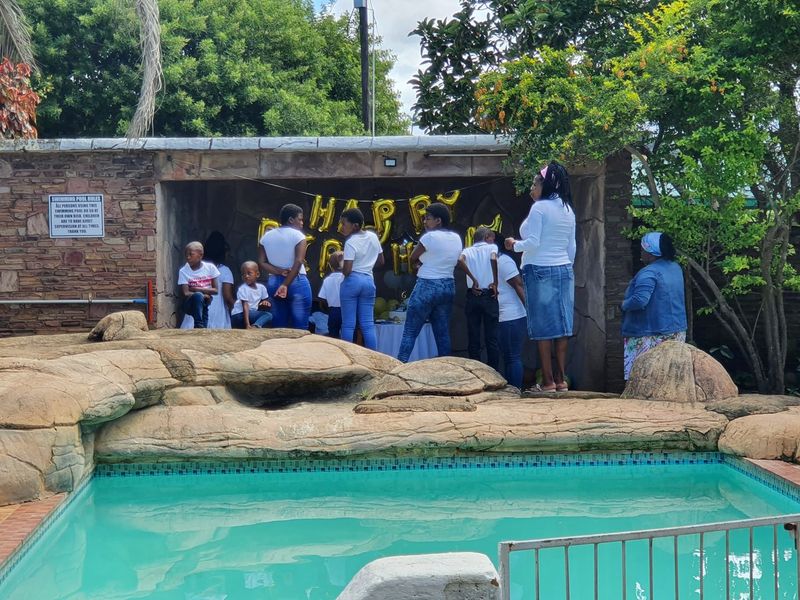 Outdoor pool area featuring a swimming pool with natural rock landscaping and a covered stone-clad patio space.