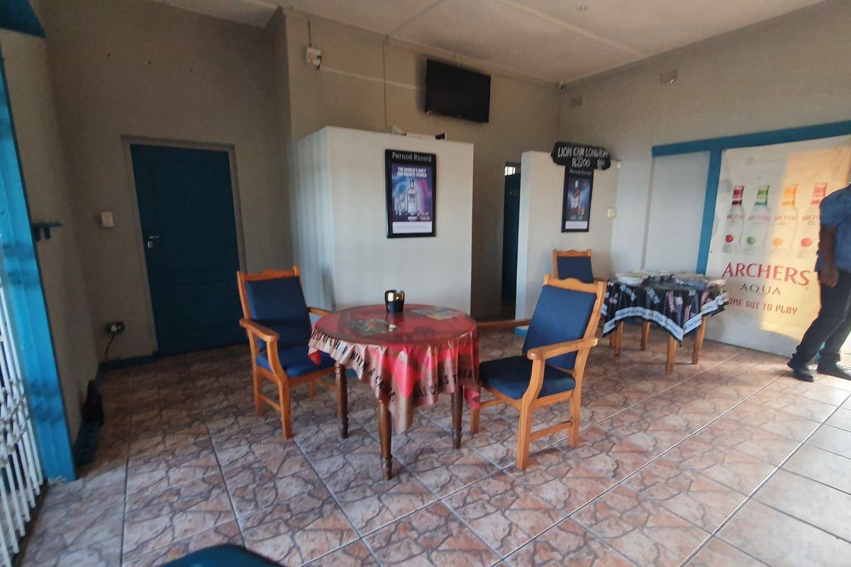 A commercial interior space featuring tiled flooring and security gate access, suitable for a bar or lounge area.
