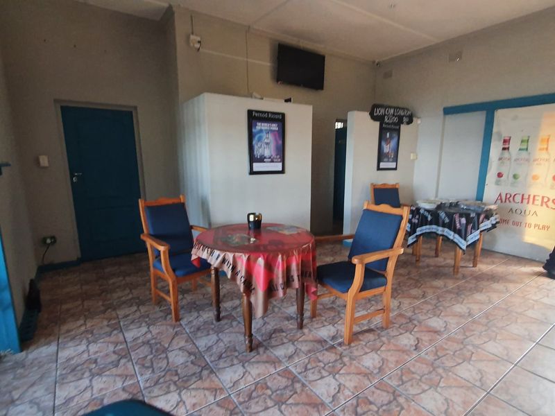 A commercial interior space featuring tiled flooring and security gate access, suitable for a bar or lounge area.