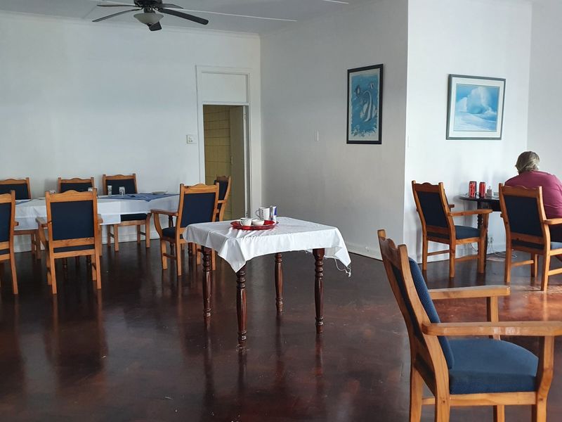 Spacious dining area featuring polished hardwood flooring and a ceiling fan, providing a functional layout for commercial or hospitality use.