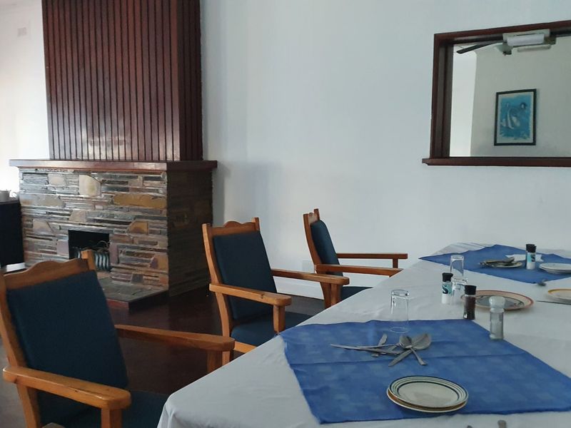 Dining area featuring a prominent stone fireplace with timber surround and hardwood flooring, providing a traditional atmosphere for commercial or hospitality use.