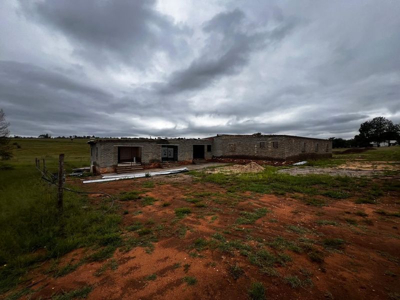 A rear view of a commercial property under construction, featuring exposed brickwork and an unfinished exterior on a large rural plot.