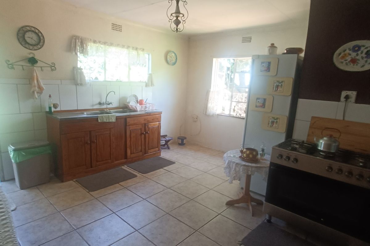 A functional kitchen featuring wooden cabinetry, a double sink, tiled flooring, and a gas stove, offering a classic layout with potential for modernization.