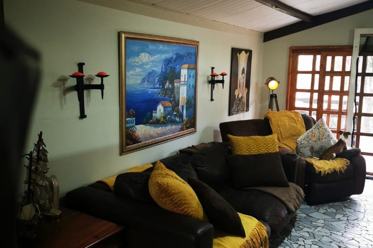 Living room featuring exposed timber ceiling beams, unique stone mosaic flooring, and a timber-framed glass door leading to the exterior.