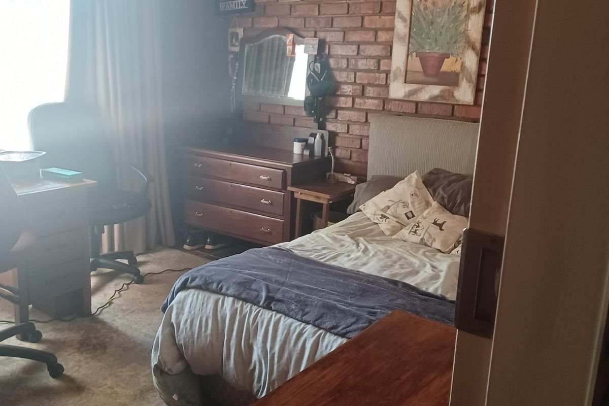 A bedroom featuring exposed brick walls and a timber-paneled ceiling, offering a rustic aesthetic with tiled flooring.