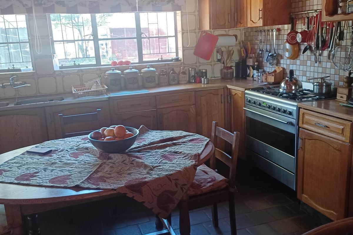 A rustic kitchen featuring wooden cabinetry, tiled backsplash, a gas stove, and a dedicated dining area with tiled flooring.
