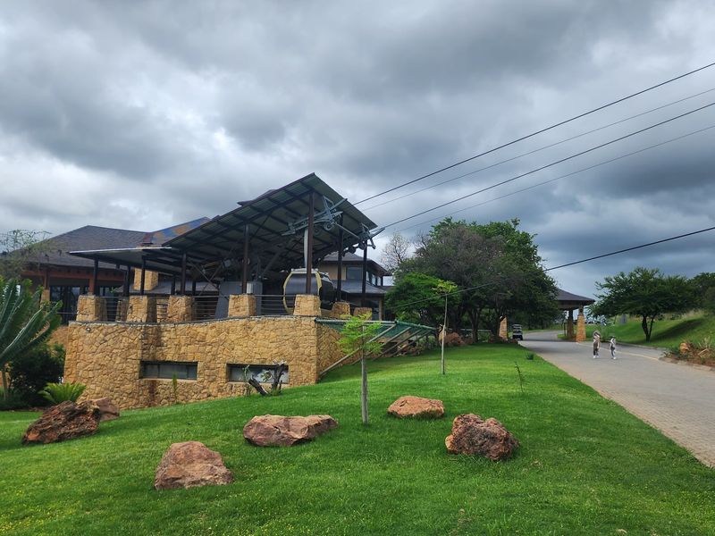Exterior view of a property featuring stone cladding, a paved driveway, and integrated cable car infrastructure set within a landscaped garden.