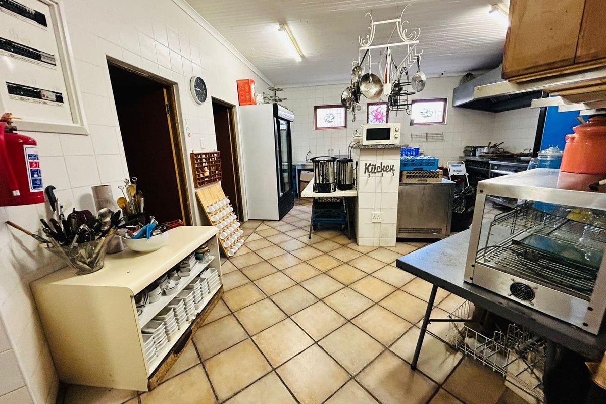 A functional commercial kitchen space featuring tiled flooring, wall-mounted cabinetry, and professional-grade extraction systems, suitable for high-volume food preparation.