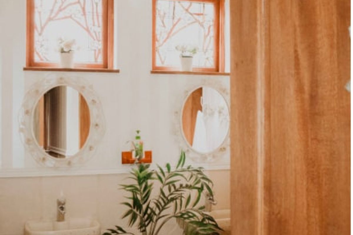 A well-maintained bathroom featuring dual pedestal sinks, decorative wall-mounted mirrors, and timber-framed windows, providing a classic and functional aesthetic.