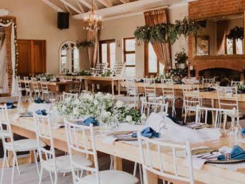 Spacious open-plan commercial venue featuring exposed timber beams, a prominent brick fireplace, and large arched windows, ideal for events and gatherings.