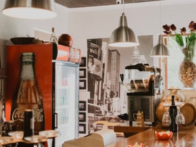 A commercial bar area featuring a polished wooden counter, pendant lighting, and a dark timber panelled ceiling, creating a warm and inviting atmosphere.