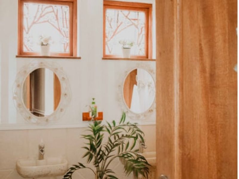 A well-maintained bathroom featuring dual pedestal sinks, decorative wall-mounted mirrors, and timber-framed windows, providing a classic and functional aesthetic.