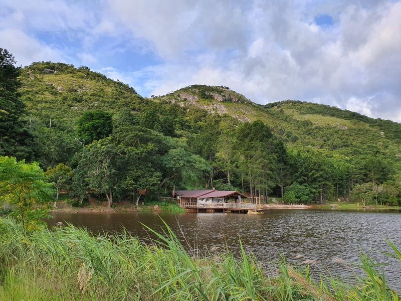 A scenic view of a lakeside property featuring a timber deck structure nestled against a lush, mountainous landscape.