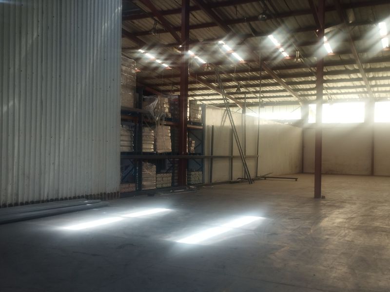 Spacious industrial warehouse unit featuring high ceilings, concrete flooring, steel portal frame construction, and integrated industrial racking systems.