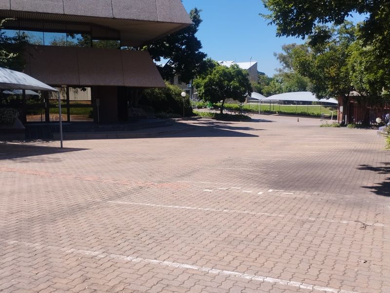 Commercial property exterior featuring a large paved parking area with shade cloth carports and established garden surroundings.