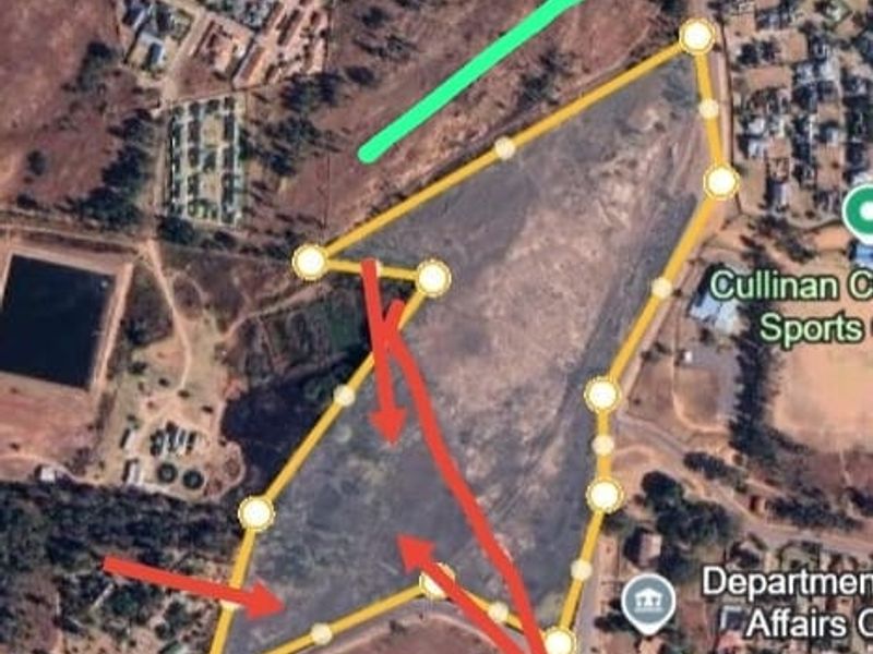 An aerial satellite view of a large commercial land parcel with boundary markers and directional arrows indicating site access and layout.
