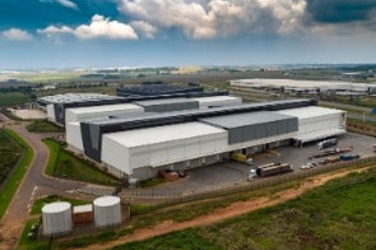 Aerial view of a large industrial warehouse facility featuring extensive loading bays, paved yard space, and perimeter security fencing.