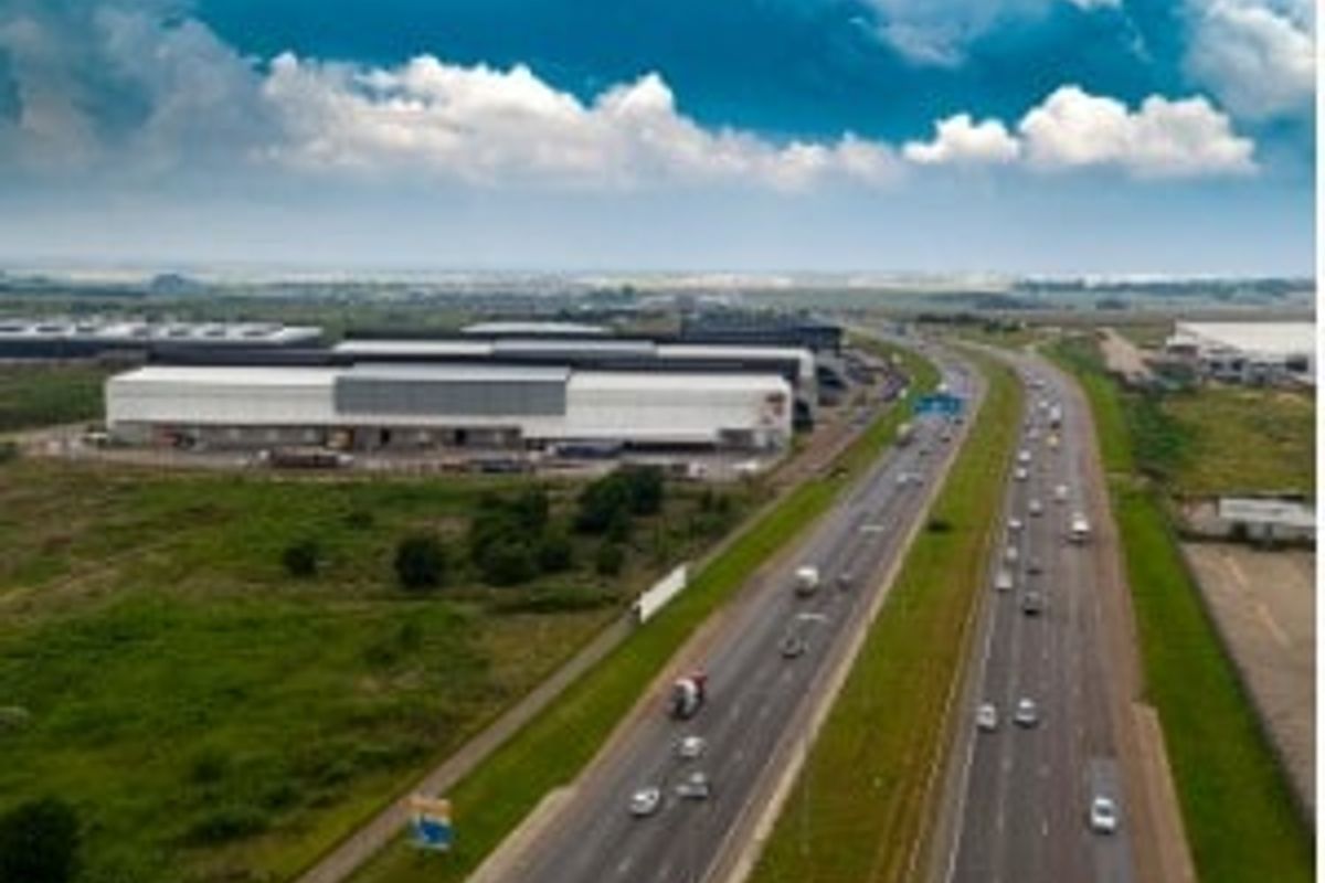 Aerial view of an industrial warehouse facility situated adjacent to a major highway, offering excellent logistical access and visibility.