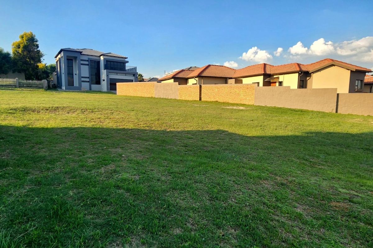 A spacious, level vacant residential plot featuring established grass lawn and secure perimeter walling in a developed neighborhood setting.