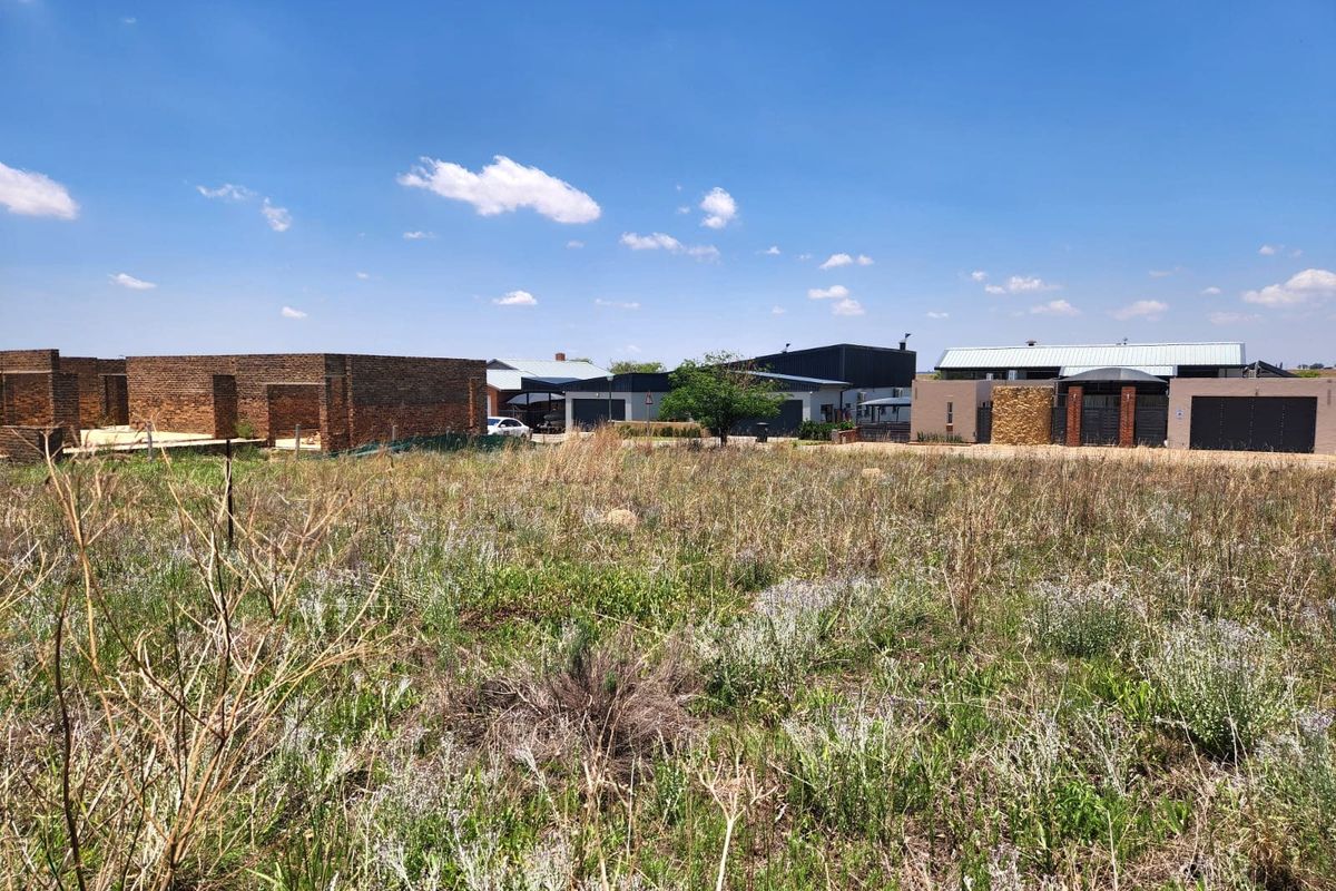 A view of a vacant residential plot with surrounding neighborhood development visible in the background.