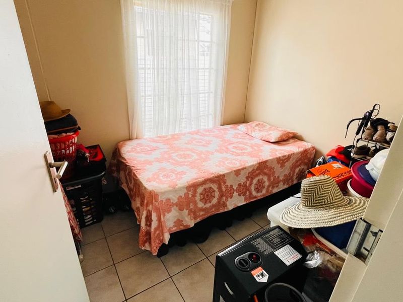 A compact bedroom featuring tiled flooring and a window with natural light, providing a functional space for a single bed.