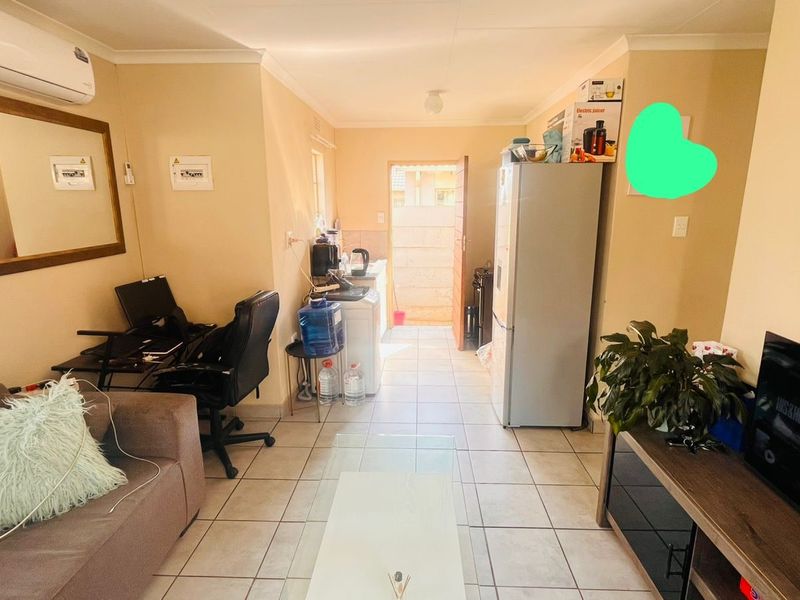 Open plan living area featuring tiled flooring and wall-mounted air conditioning unit, providing a functional space with direct access to the exterior.