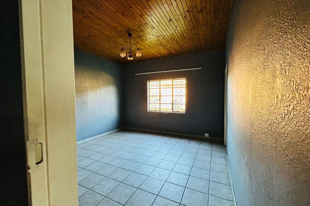 An empty bedroom featuring a timber tongue and groove ceiling, ceramic tiled flooring, and security burglar bars on the window.