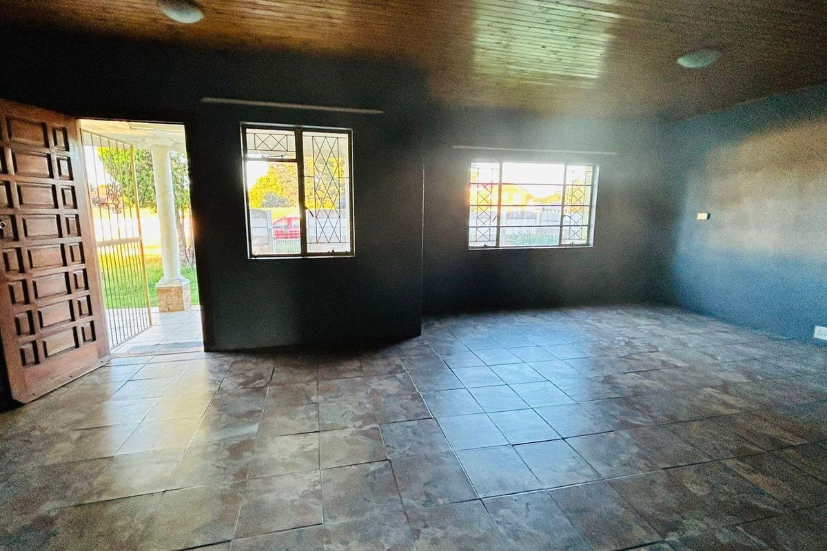 An empty living room featuring tiled flooring, a timber ceiling, and security-fitted windows and doors.