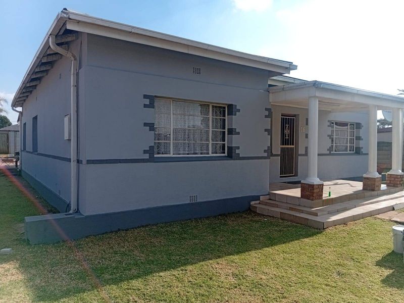 Front elevation of a single-story house featuring a covered porch with concrete columns, tiled entrance steps, and secure metal window frames.