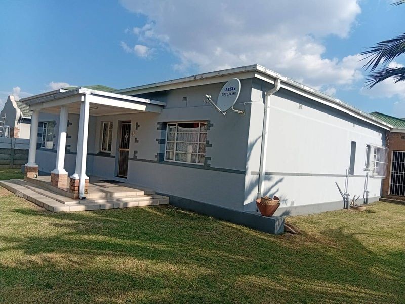 Front elevation of a single-story house featuring a covered porch with concrete columns, tiled steps, and a well-maintained lawn.
