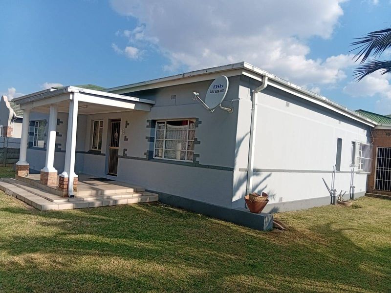 Front elevation of a single-story house featuring a covered porch, concrete columns, and well-maintained exterior walls with security features.