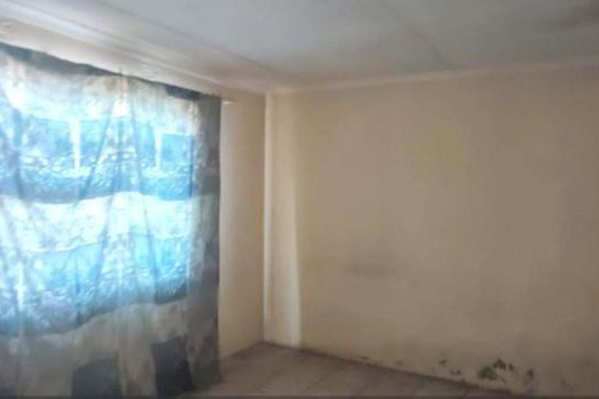 An empty bedroom featuring a window and visible wall damage, requiring maintenance and cosmetic updates to restore the space.