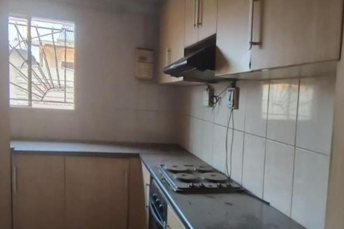 A compact kitchen featuring built-in cabinetry, an electric hob, oven, and extractor fan, requiring cosmetic updates to improve its overall condition and appeal.