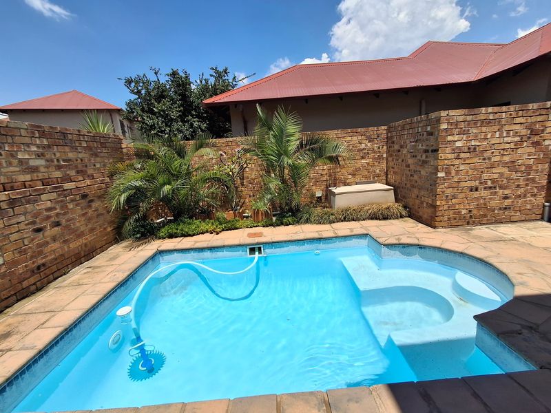 Private outdoor pool area featuring a paved surround and enclosed by high brick boundary walls, providing a secluded space for relaxation.