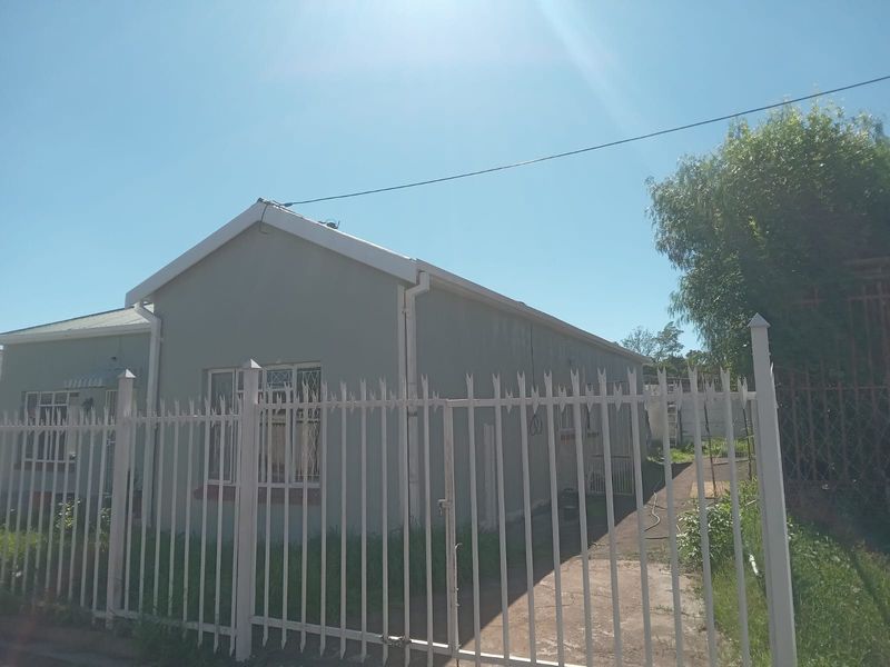 Front exterior view of a residential house featuring a metal security fence, gated entrance, and concrete driveway under a gabled roof.