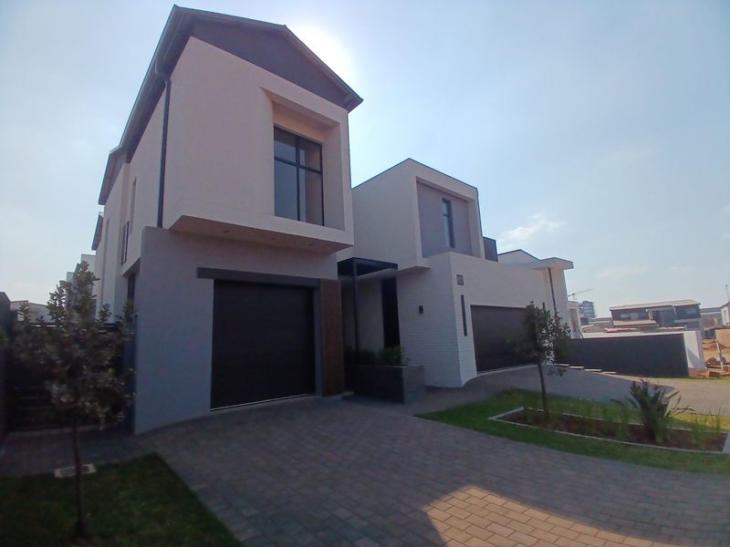Modern double-story residential property featuring a contemporary facade, paved driveway, and integrated double garages in a well-maintained estate setting.