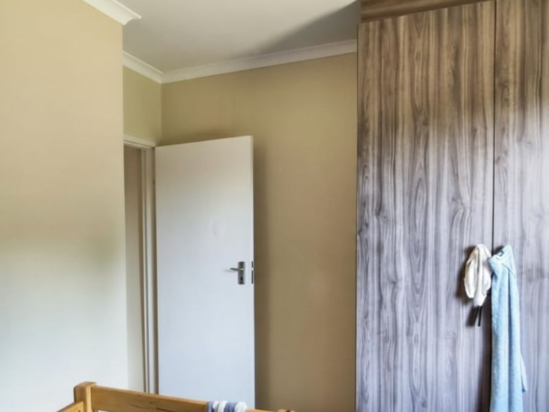 A bedroom featuring a wood-grain finish built-in wardrobe and neutral wall paint, providing functional storage space.