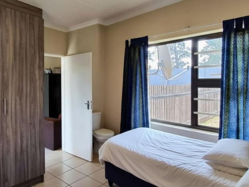 A bedroom featuring tiled flooring, a built-in wardrobe, and an aluminium window with security bars, offering a functional living space.