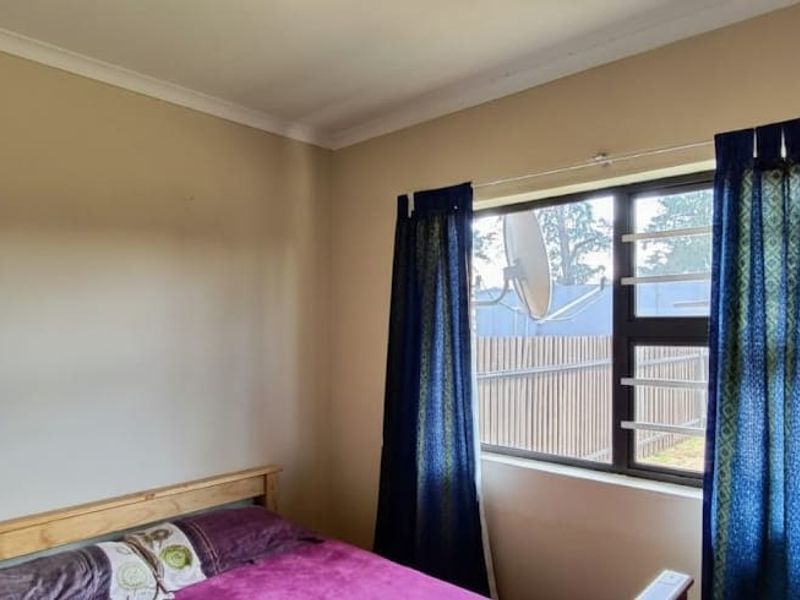 A standard bedroom featuring a window with security bars and simple cove cornicing, providing a functional and neutral living space.