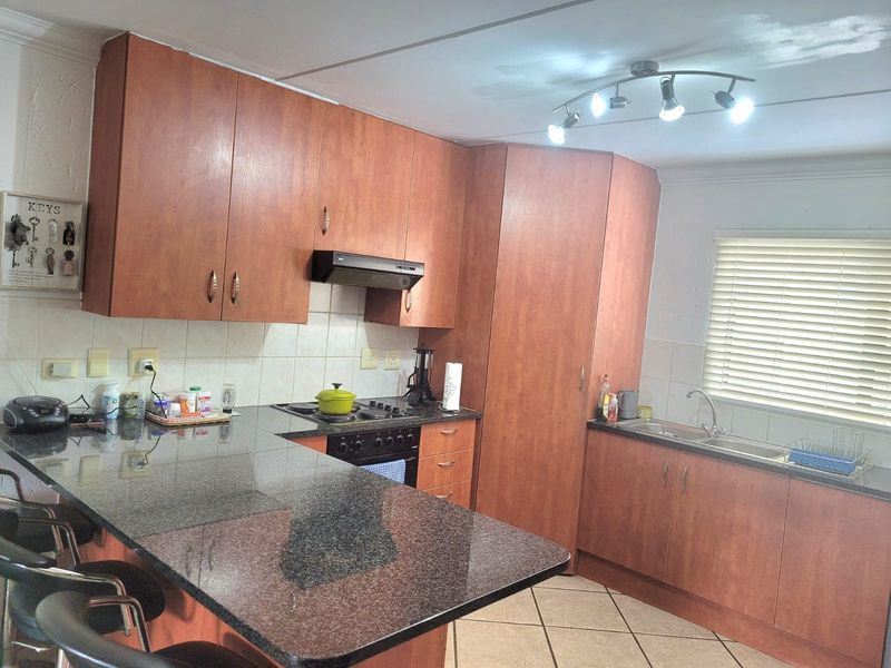 Functional kitchen featuring wood-look laminate cabinetry, granite countertops, built-in oven with extractor fan, and a breakfast bar peninsula.