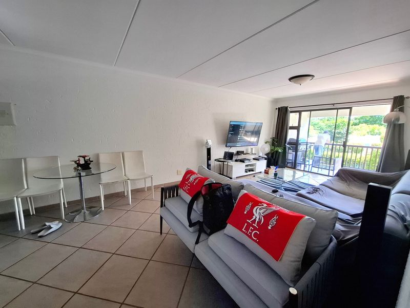 Open-plan living area featuring tiled flooring and a large sliding glass door providing access to an outdoor balcony.