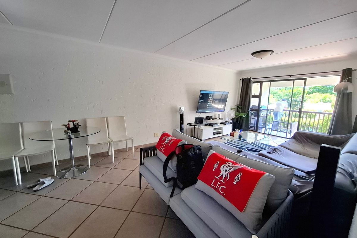 Open-plan living area featuring tiled flooring and a large sliding glass door providing access to an outdoor balcony.