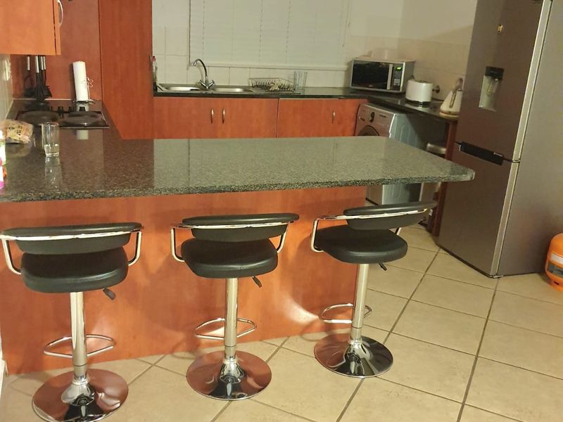 Functional kitchen featuring granite countertops, laminate cabinetry, and a breakfast bar, providing a practical layout for daily cooking and casual dining.