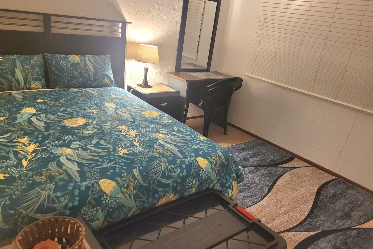 A functional bedroom featuring textured walls and venetian blinds, providing a neutral base for potential interior updates.