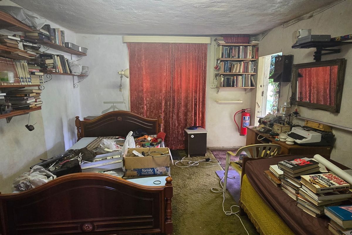 A bedroom featuring wall-mounted shelving and carpet flooring, requiring cosmetic updates and repairs to the wall and ceiling finishes.