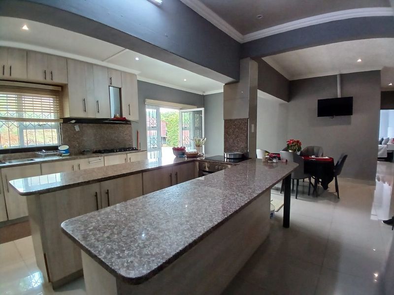 Spacious open-plan kitchen and dining area featuring granite countertops, ample built-in cabinetry, a central kitchen island, and modern tiled flooring.